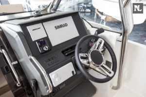 Puesto de mando interior del Nimbus T8, con volante, pantallas Mercury y Simrad, controles y parabrisas.