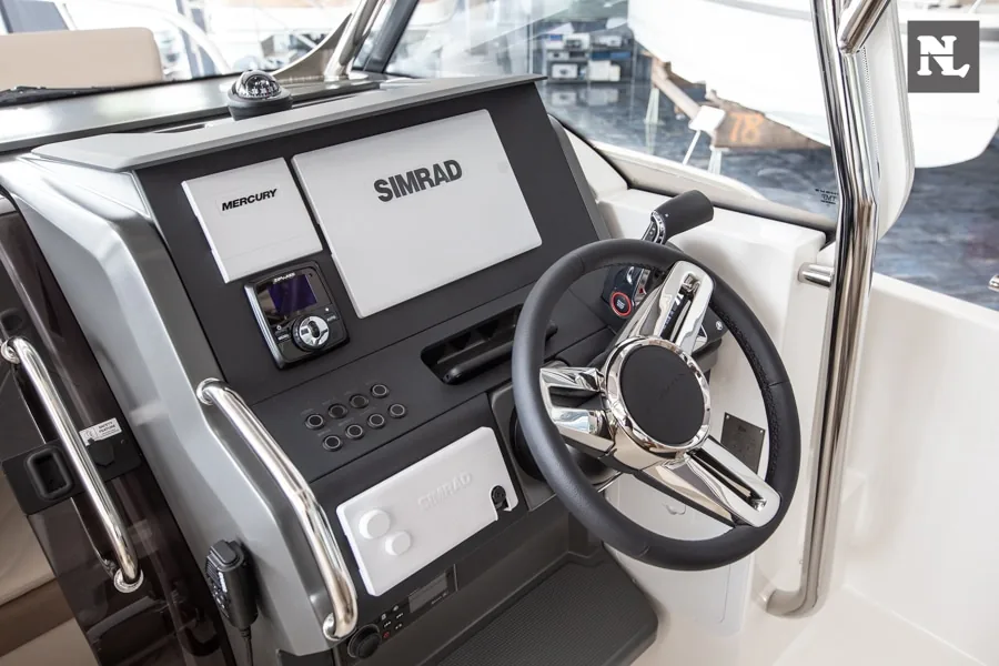 Puesto de mando interior del Nimbus T8, con volante, pantallas Mercury y Simrad, controles y parabrisas.