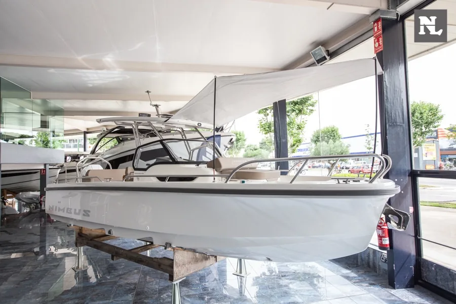 NIMBUS T8 TAUPÉ visto de perfil en interior, con consola, techo rígido, toldo y barandilla de proa visibles