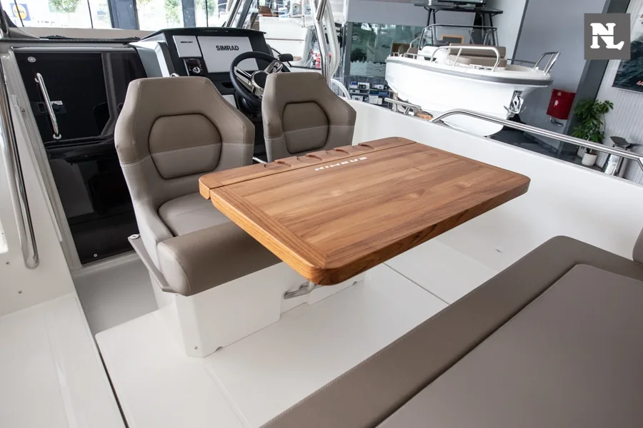 Interior del Nimbus T8 Taupe 26, con mesa de madera, asientos del puesto de mando y banco lateral.