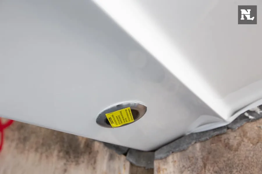 Detalle exterior del Nimbus T8 Taupe: etiqueta amarilla de advertencia en el casco, vista en ángulo bajo.