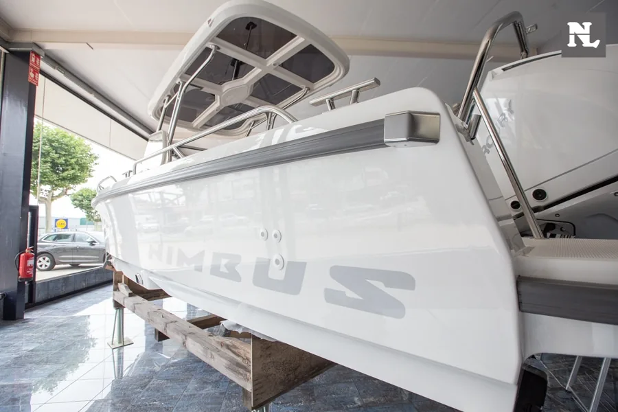 Barco Nimbus T8 visto de costado en exposición, con parabrisas, consola de mando y plataforma trasera visibles.