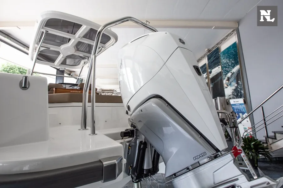 Popa del Nimbus T8 con motor fueraborda, plataforma de baño y puesto de gobierno visibles desde el interior.