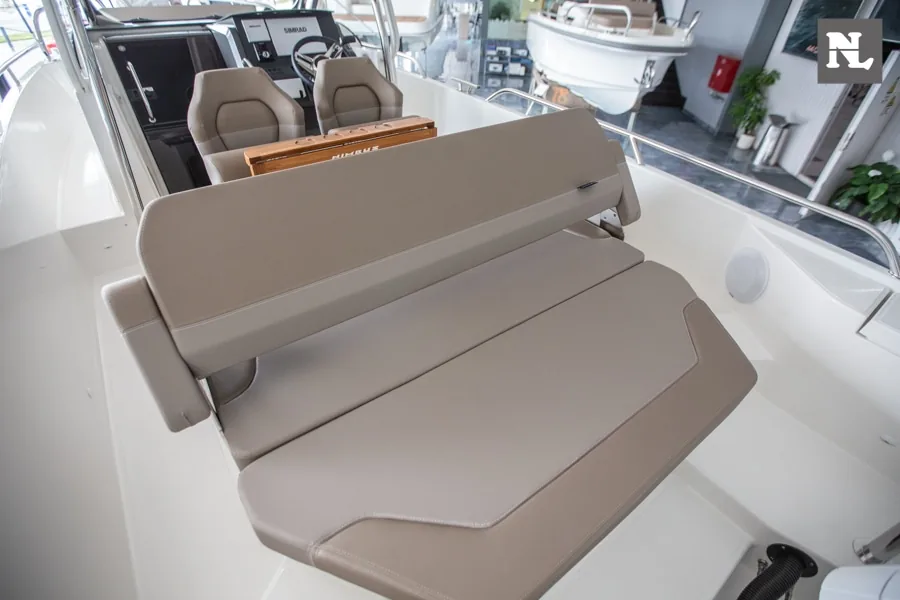 Nimbus T8, vista del interior de popa con asientos tapizados en tono topo y puesto de mando al fondo.