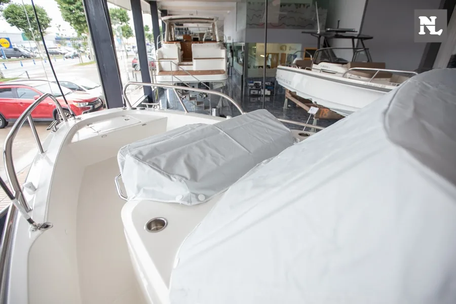 Nimbus T8: vista de la cubierta exterior de proa con solárium y lonas protectoras en exposición náutica.