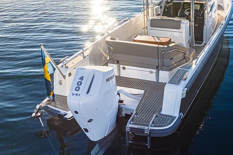 Nimbus T9 vom Heck aus gesehen, mit Außenbordmotor, schwedischer Flagge, Sitzen und Badeplattform über dem Wasser.