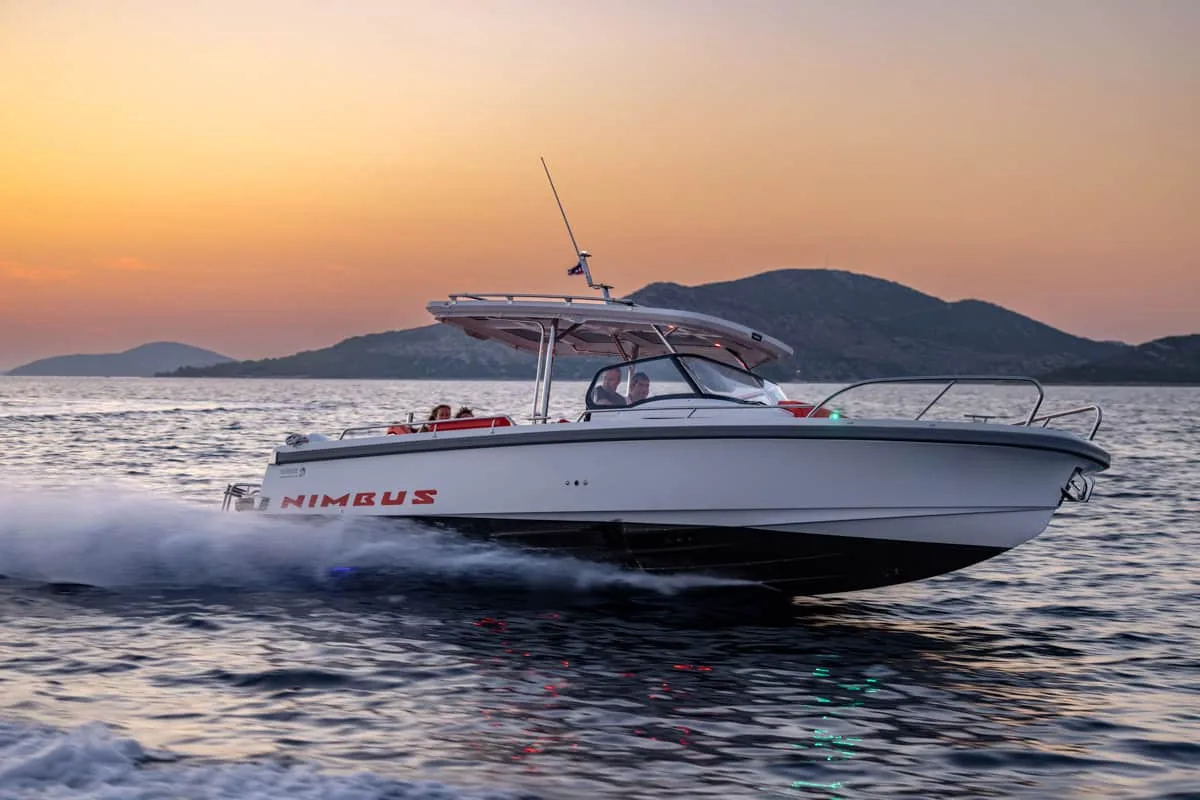 T9-GALERIE-12 Nimbus T9 fährt bei Sonnenuntergang in Seitenansicht, mit Hardtop, Windschutzscheibe, Reling und einer Heckwelle auf dem Wasser