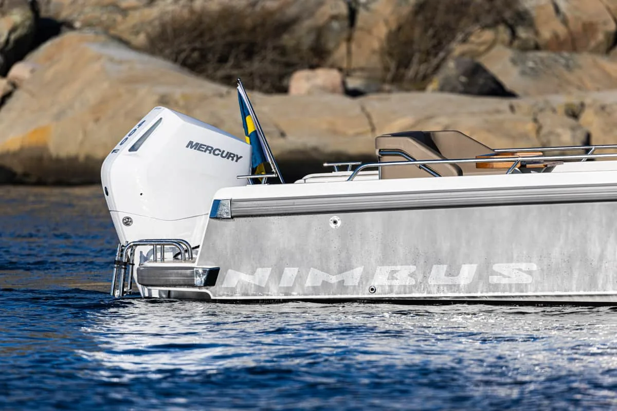 T9-GALERIE-2 Seitenansicht des Hecks der Nimbus T9 mit einem Mercury-Außenbordmotor, Reling und einer felsigen Küste im Hintergrund