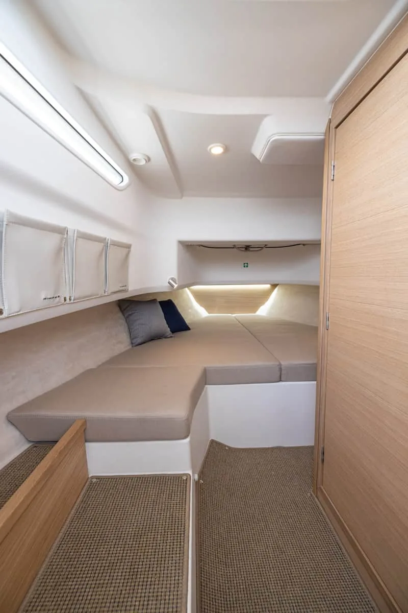 T9-GALERIE-9 Innenraum der Kabine des Nimbus T9 mit U-förmigem Bett, Polstern, Schränken und Holztür.