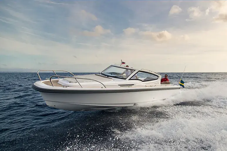 Nimbus W9 navegando de perfil, con cubierta exterior, cabina cerrada y estela sobre el mar