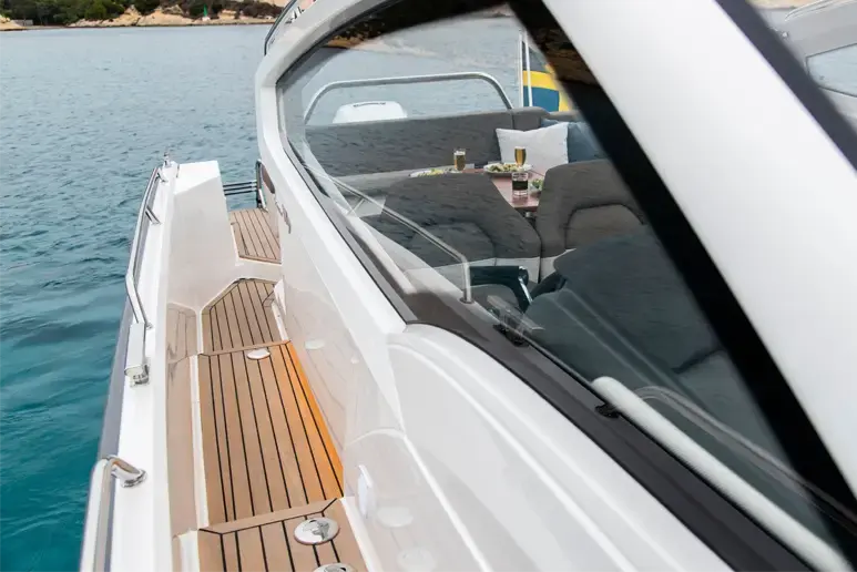 Exterior del Nimbus W9 visto de proa, con cubierta lateral de teca y zona de asientos bajo parabrisas.