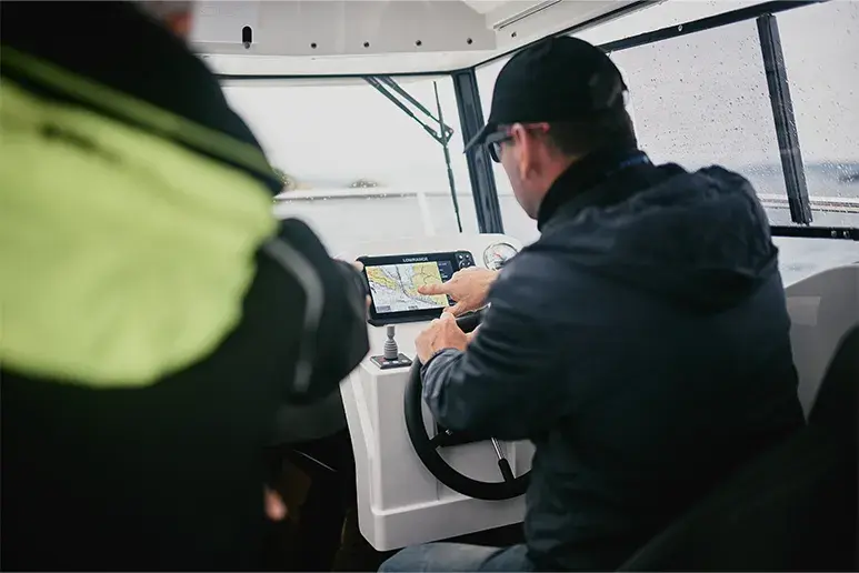 Interior del Parker 700 Pilothouse, vista del puesto de mando con dos personas y pantalla de navegación.
