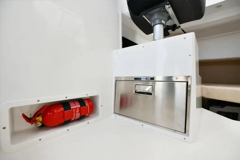 Interior del Parker 700 Pilothouse, con extintor rojo empotrado y escotilla de acero inoxidable bajo un asiento.