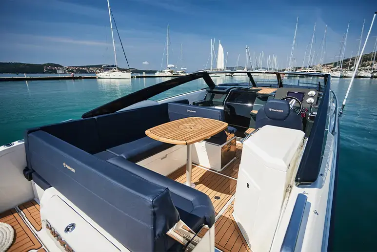 Interior exteriorizado de Parker 780 Escape, visto desde popa, con asientos, mesa, consola de mando y puerto al fondo