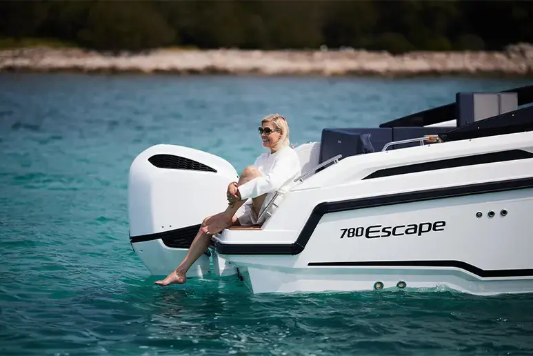 Parker 780 Escape visto de costado, con mujer sentada en la plataforma de popa y motor fueraborda en el agua.
