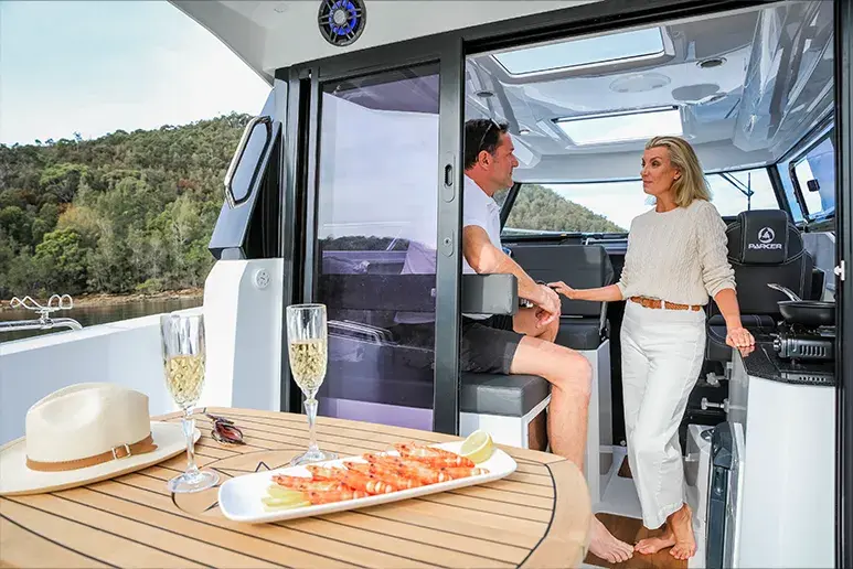 Parker 790 Explorer, Innenansicht vom Cockpit aus, mit zwei Personen, einem Tisch mit Essen und sichtbarem Steuerstand.