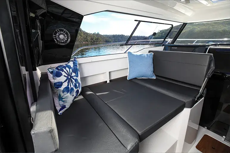 Innenraum des Parker 790 Explorer mit einem L-förmigen Sofa, Kissen und Fenstern mit Blick auf das Wasser.