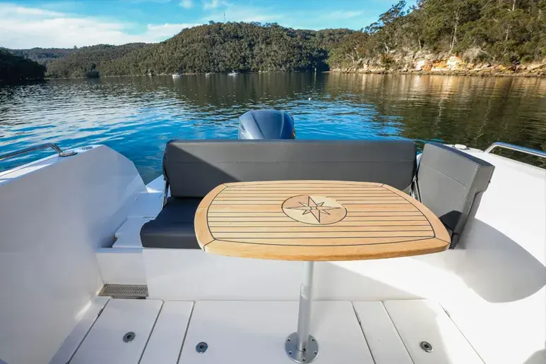 Parker 790 Explorer, Ansicht des Cockpits mit Teaktisch, Sitzen und Außenbordmotor auf einem See.