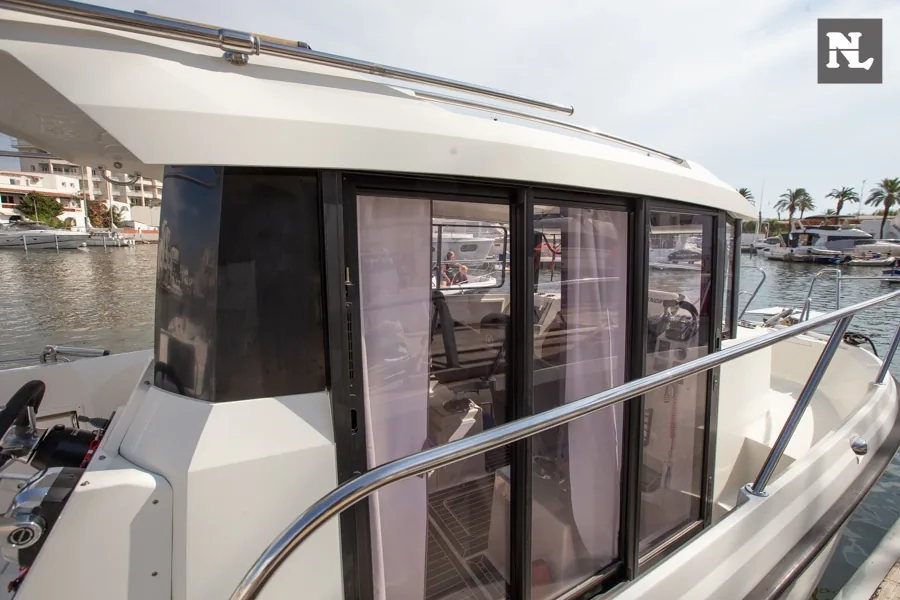 Seitliche Außenansicht der Parker 800 Pilothouse mit verglaster Kabine, Schiebetür, Reling und Hafen im Hintergrund.