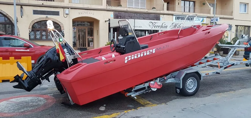 Red Pioner Multi 3, viewed from the side on a trailer, with an outboard motor.