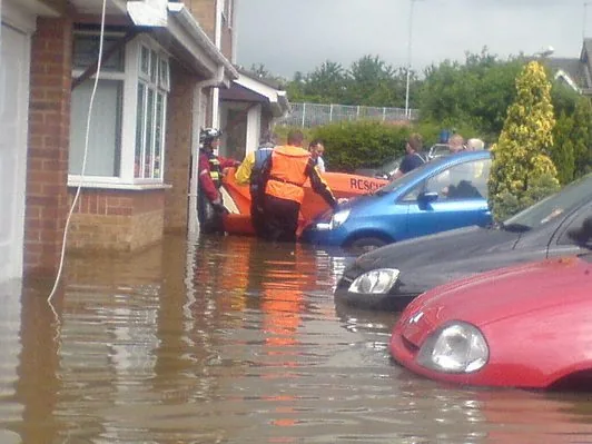 420343_10151313407342291_1127874884_n PIONER MULTI III orange outdoors, with people beside a house and cars partially submerged in floodwater.