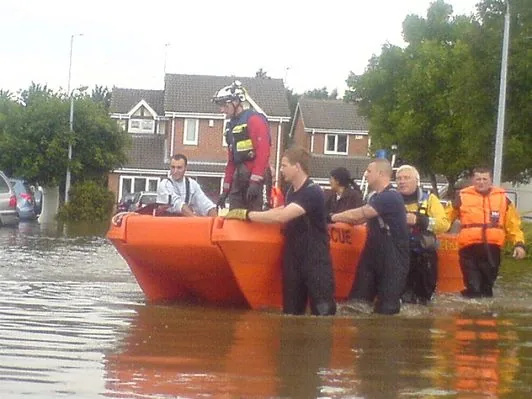 PIONER MULTI III orange outdoors, side view, with rescuers crossing floodwaters.