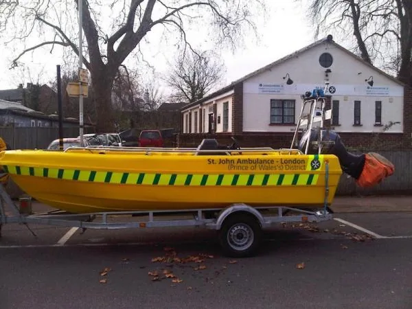 PIONER MULTI III yellow, shown in profile on a trailer, with green stripes, a center console and an outboard motor.