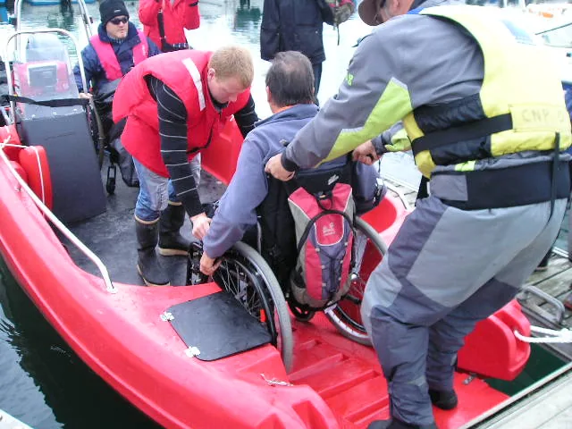 Essais Pioner Multi Etel 012 PIONER MULTI III red, seen from the outside, with people helping a passenger in a wheelchair board.