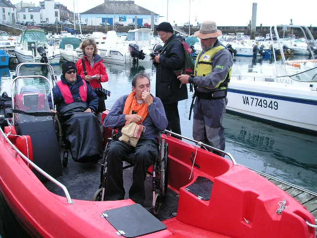 Essais Pioner Multi Etel 013 PIONER MULTI III red, interior view with two people in wheelchairs and two companions in a harbor.