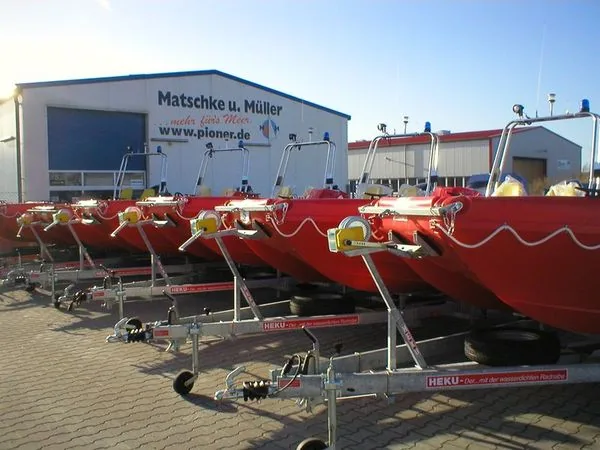 Red PIONER MULTI III boats lined up outside on trailers, viewed from the front and side.