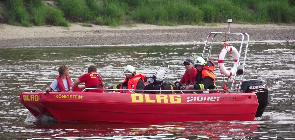 PIONER MULTI III red, exterior side view, with five people, life jackets, and a Suzuki motor on a river.