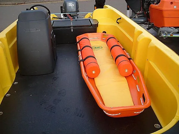 Interior of the PIONER MULTI III with an orange stretcher, black seat, and outboard motor visible from the stern