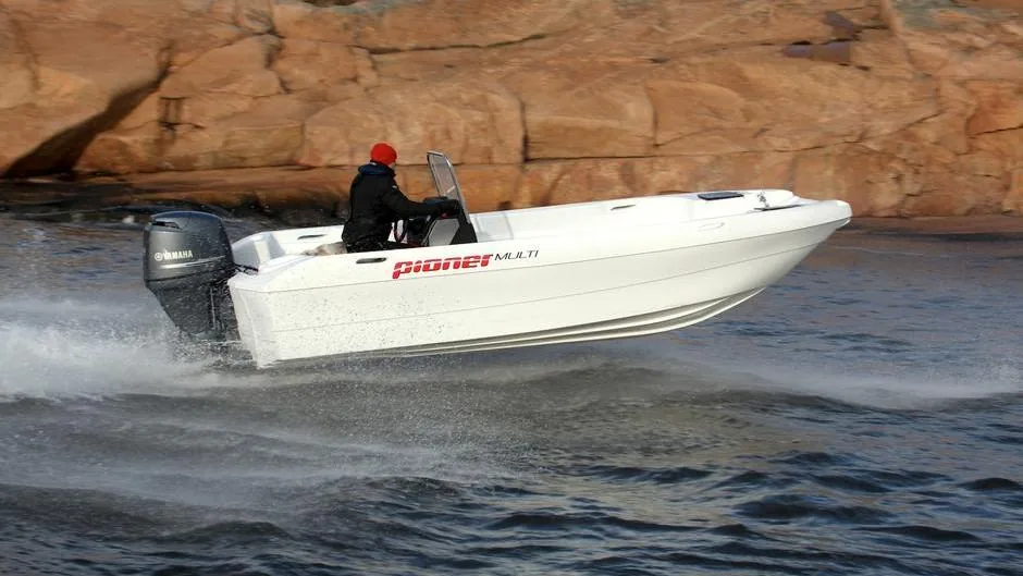 Pioner_Multi_blanco PIONER MULTI III white boat underway, exterior side view with outboard motor and pilot on board.