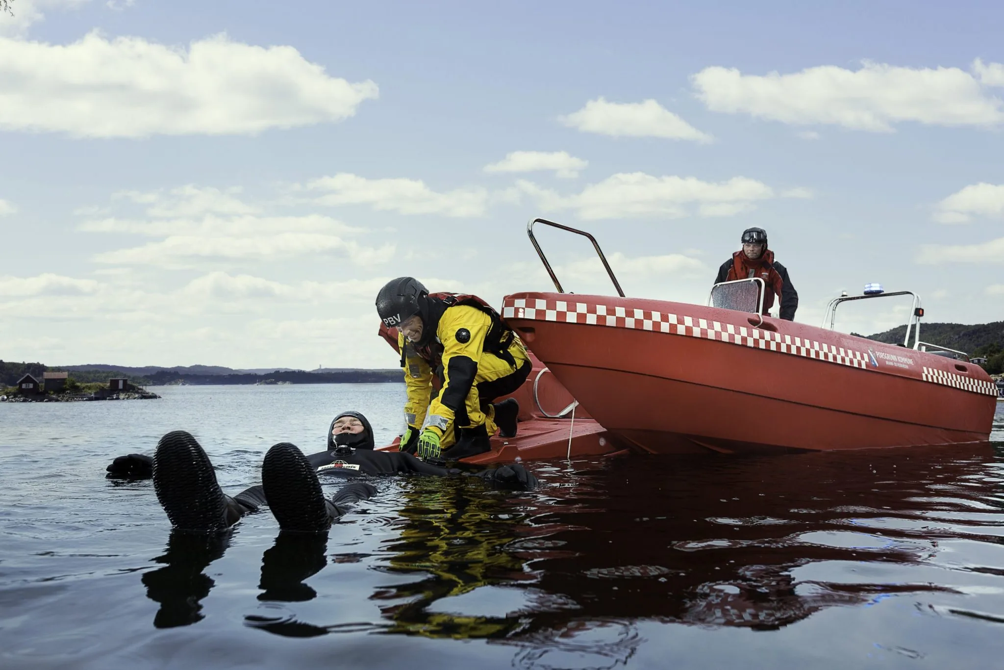 PIONER MULTI III red alongside divers in the water, seen from the side with deck and console visible