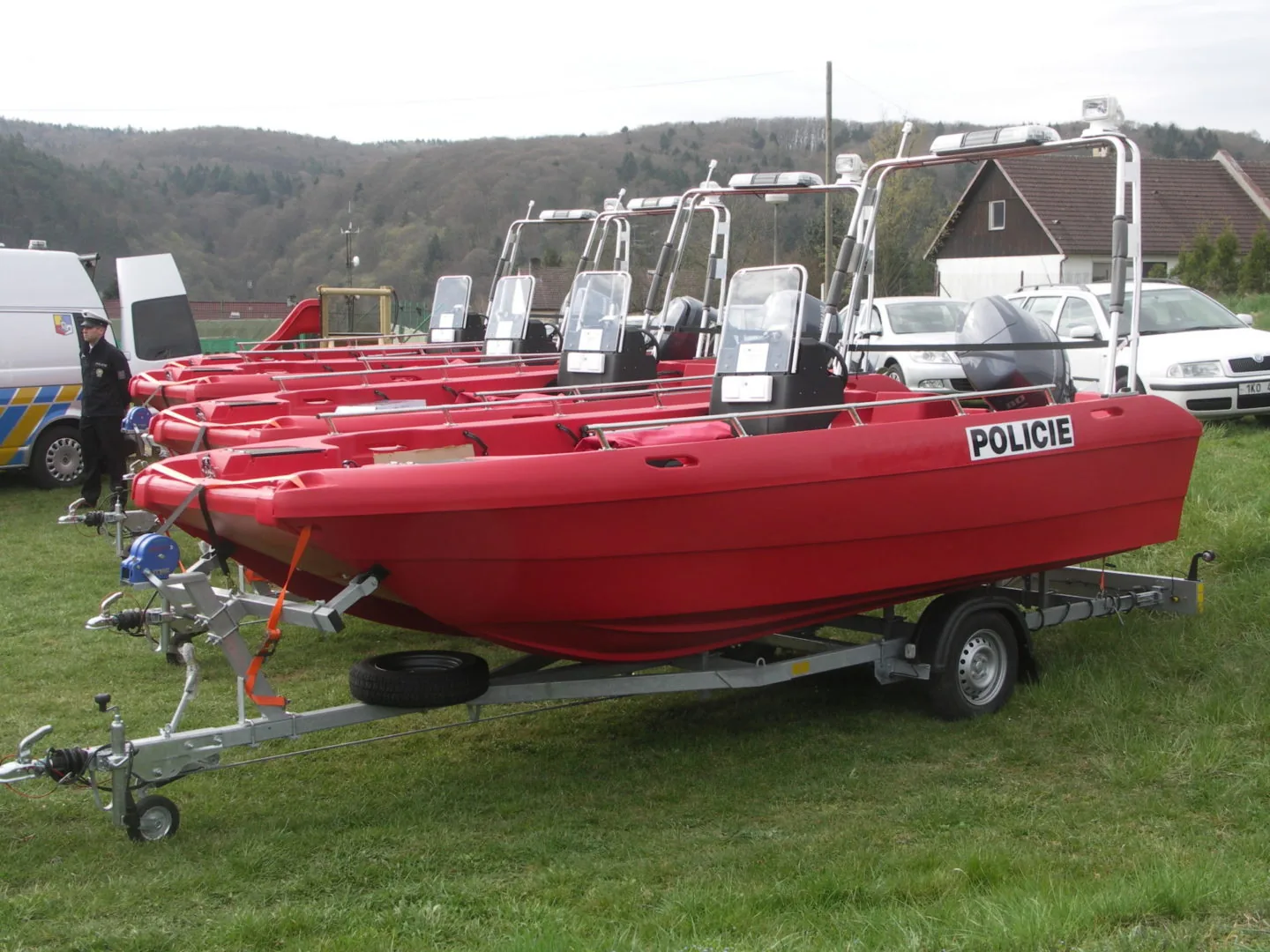Red PIONER MULTI III boats on trailers, exterior side view, with consoles, windshields, and POLICIE lettering.