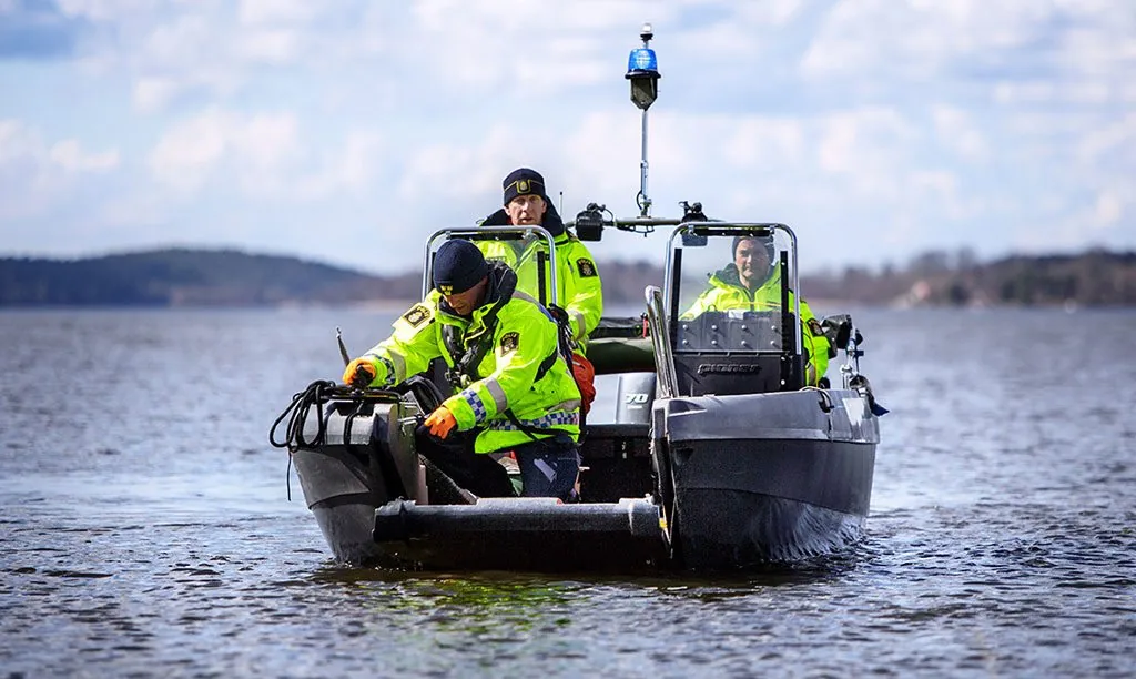 PionerMultiProff-6-1024×612 PIONER MULTI III underway head-on with three people, center console, outboard motor, and safety equipment.