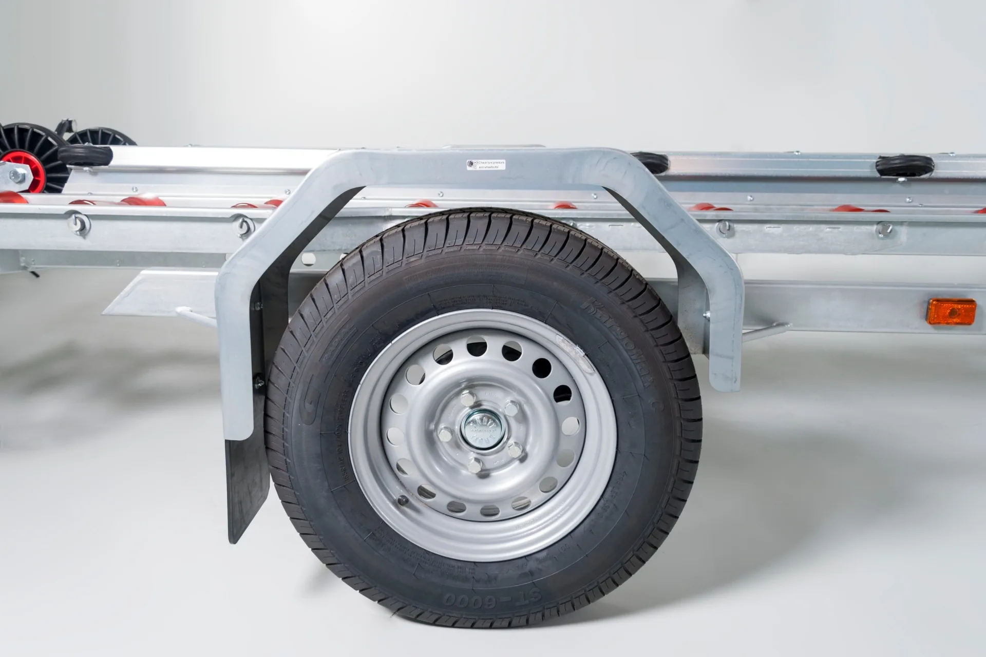 Wheel and fender of the PIONER MULTI III boat trailer, side view, with lights and metal frame visible.