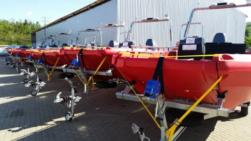 PIONER MULTI III, side exterior view of several red boats on trailers.