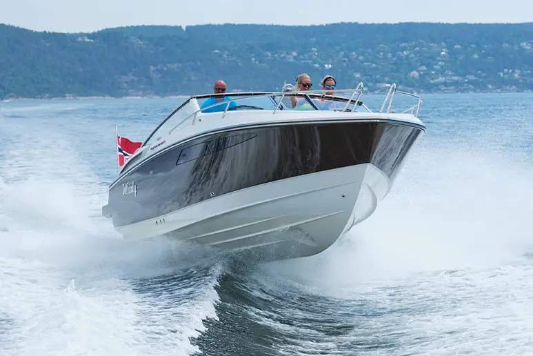 Windy 32 Grand Zonda sailing toward the viewer, exterior bow view with four people on board and a water wake