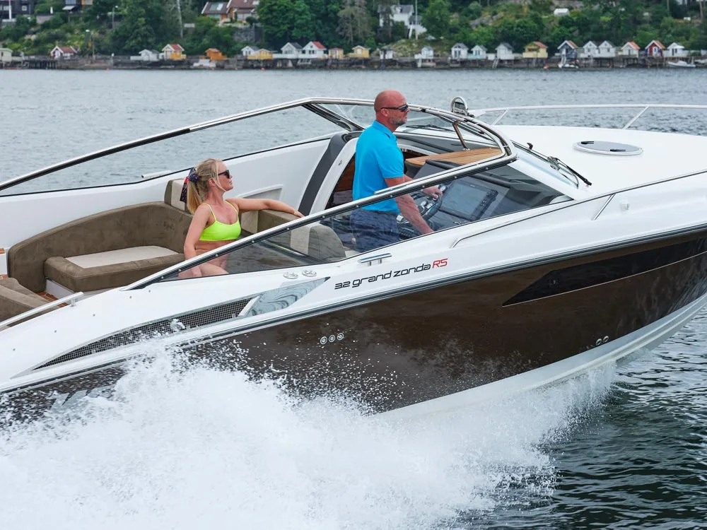 Windy 32 Grand Zonda cruising, exterior side view with two people and a wake on the water.