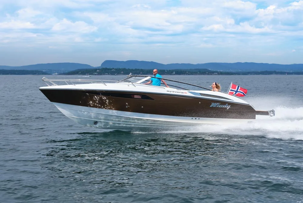 Windy 32 Grand Zonda underway in profile, with two people aboard and a Norwegian flag at the stern.
