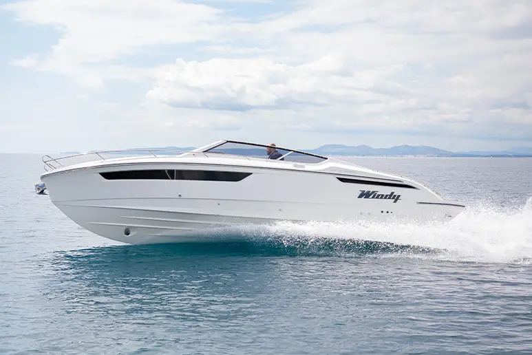 Windy 29 Huracán naviguant de profil, avec console centrale, pare-brise et coque blanche sur la mer.