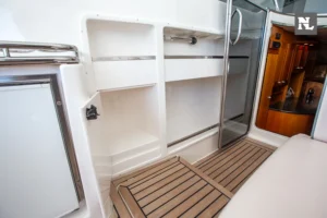 Interior del Windy 32 Scirocco con suelo de teca, armarios, puerta de baño y acceso a la cabina.