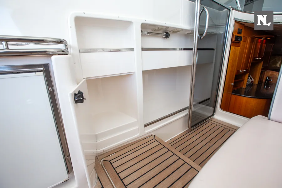 Interior del Windy 32 Scirocco con suelo de teca, armarios, puerta de baño y acceso a la cabina.