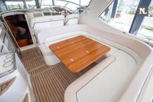 Windy 32 Scirocco, vista del cockpit con mesa de teca, sofás, puesto de mando y acceso a cabina.
