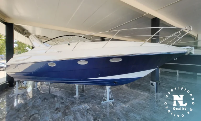 Exterior lateral de Windy 32 Scirocco en exposición, sobre soportes, con casco azul y cubierta blanca.