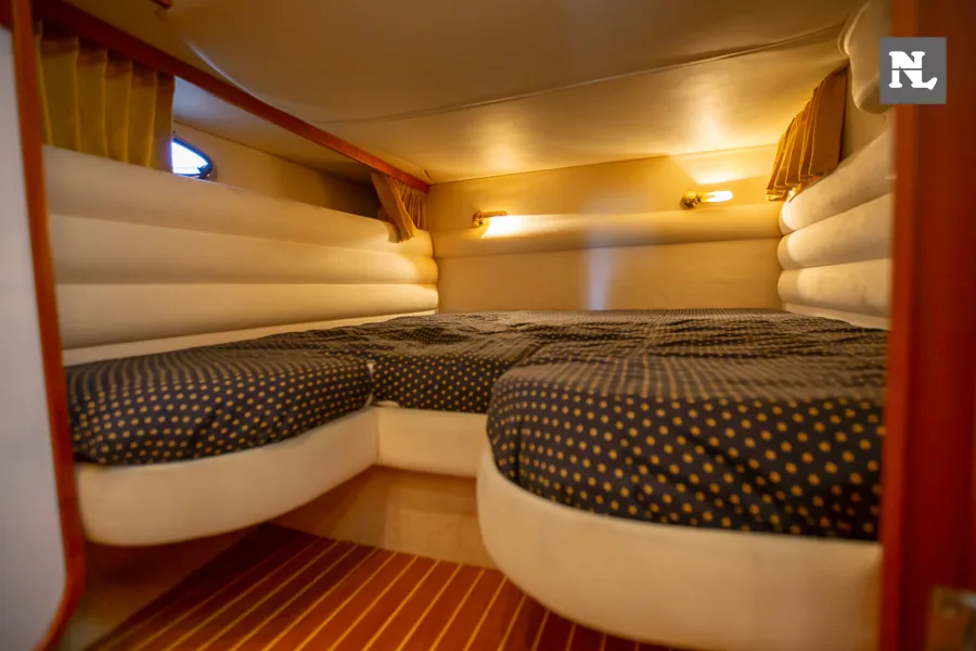 Interior del Windy 32 Scirocco, cabina con dos literas tapizadas y suelo de madera.