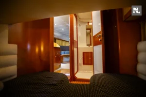 Interior del Windy 32 Scirocco visto desde una cabina, con literas, pasillo, baño y mobiliario de madera.
