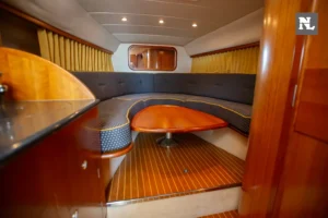Interior del Windy 32 Scirocco, visto desde la entrada, con salón en U, mesa central y suelo de madera.