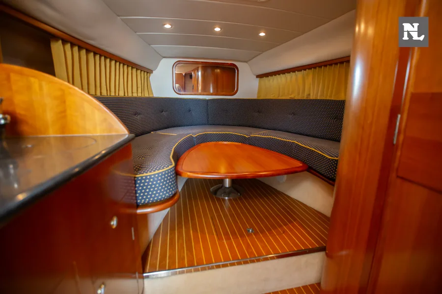 Interior del Windy 32 Scirocco, visto desde la entrada, con salón en U, mesa central y suelo de madera.